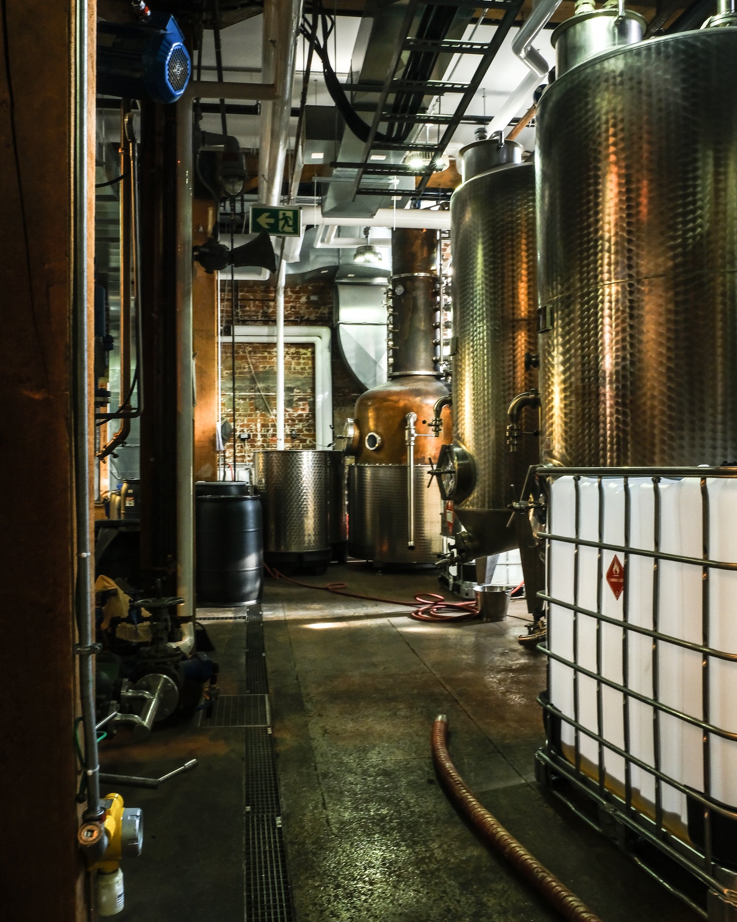 Industrial interior with large metal tanks and pipes in an active distillery setting